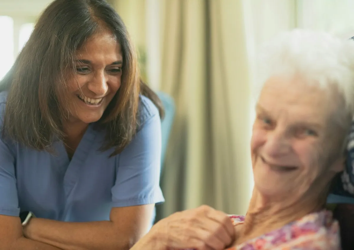Pflegekraft und Seniorin lachen gemeinsam