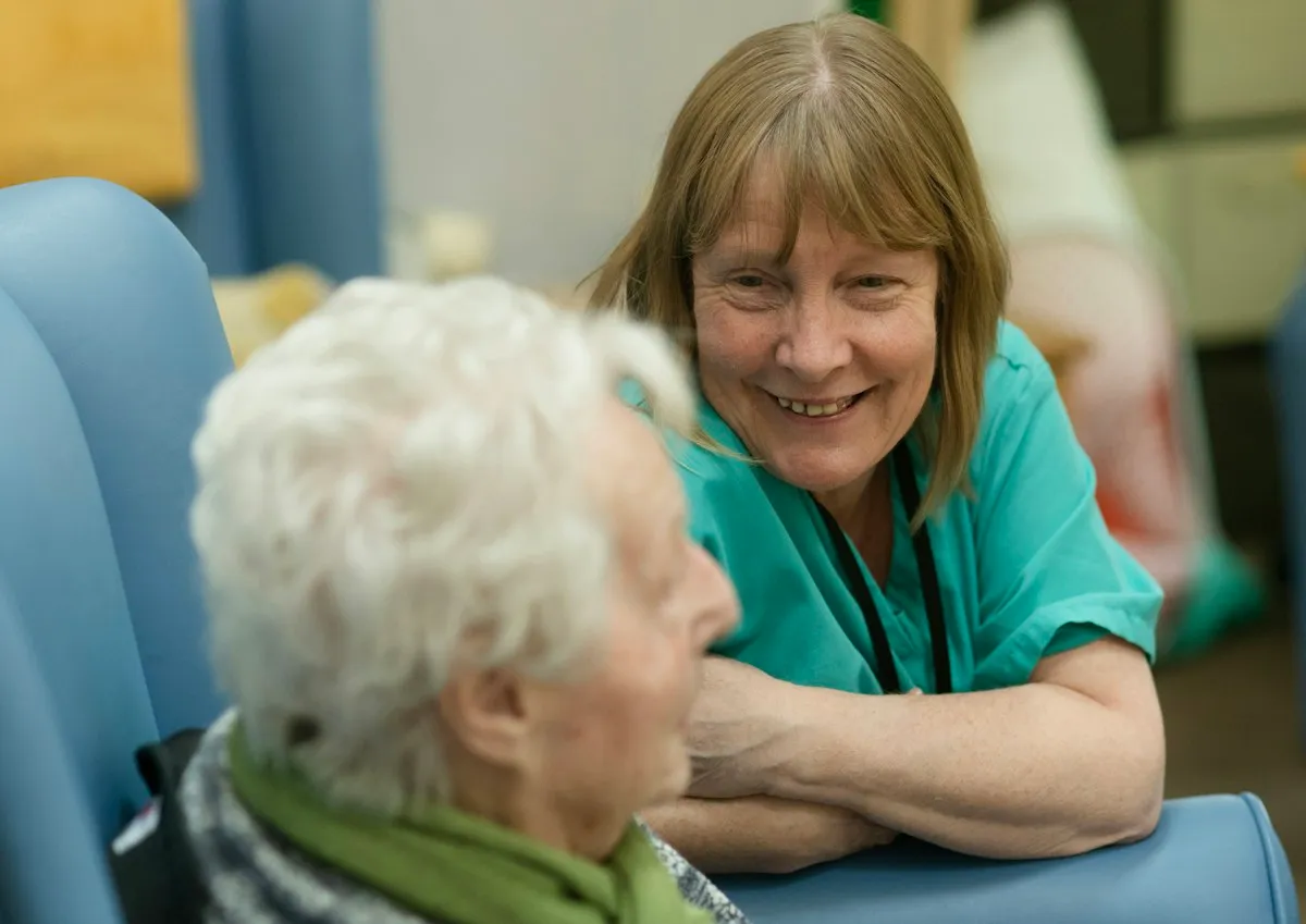 Betreuerin im freundlichen Gespräch mit einer Seniorin